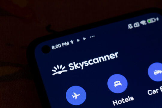 Warsaw, Poland - November 6, 2025: Close-up of a smartphone screen showing the Skyscanner logo and app icons for searching flights, hotels, and car rentals.