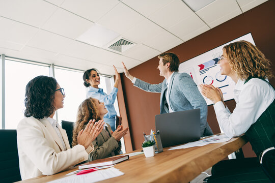 Business team celebrates success in modern office workspace with teamwork and collaboration - Powered by Adobe