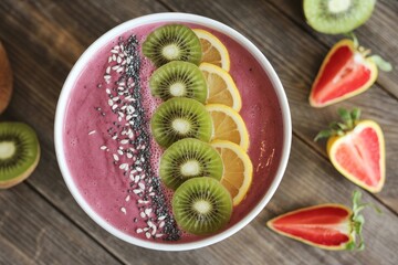 Colorful smoothie bowl topped with fruits and seeds on a wooden table