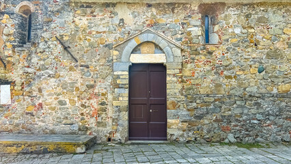 Old Stone Building with Door: An intriguing doorway graces a weathered stone building, its architectural details telling tales of history, with a weathered stone facade.