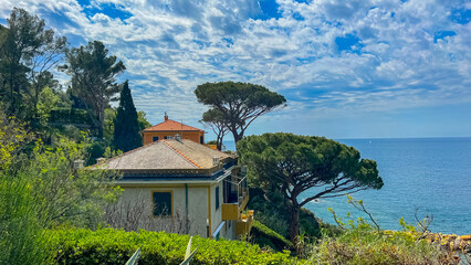 Coastal Villa Serenity: A picturesque villa nestled on a verdant hillside overlooking a tranquil expanse of sea, inviting a sense of peace and wonder.