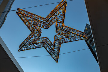 Glowing Star Decoration in Cityscape: A large, radiant star decoration illuminates the twilight cityscape. The architectural design of the buildings creates a visual contrast.