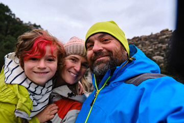 Happy family wearing warm clothes taking a selfie during a day out in nature.