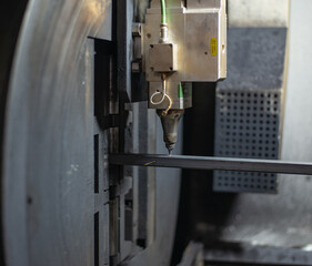 Laser pipe cutter in operation. The laser head burns through the metal profile, throwing sparks. High quality photo