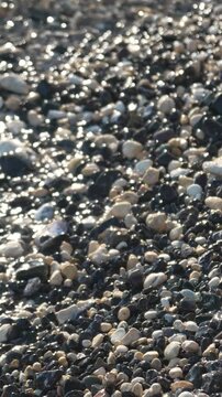 Water Pebbles Beach Waves washing over glittering stones on a rocky shore sparkling with sunlight reflections Vertical video