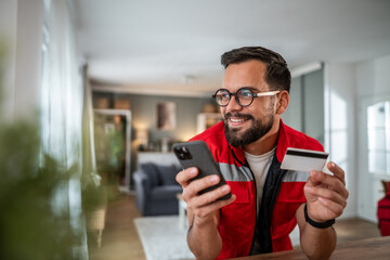 Man shopping online using smartphone and credit card at home