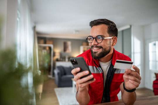 Man shopping online using smartphone and credit card at home
