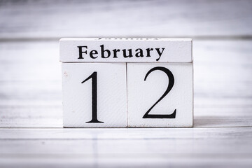 A wooden calendar displaying February 12, highlighting the month and day clearly. This scene evokes themes of time management and organization.