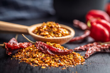 Red chili peppers flakes. Milled spicy peppers on black table.