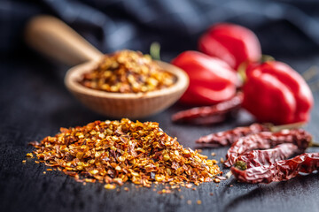 Red chili peppers flakes. Milled spicy peppers on black table.