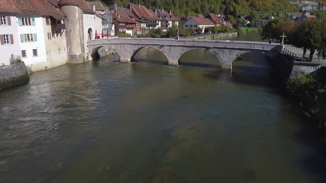 Aerial view revealing the medieval town of Saint Ursanne and its historic bridge over the Doubs river