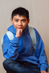 Young student with backpack resting chin on hand
