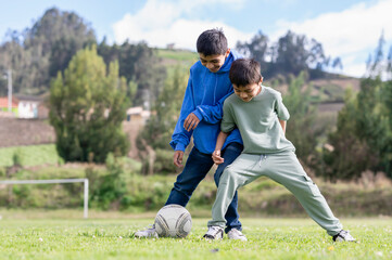 Two boys playing soccer on green field