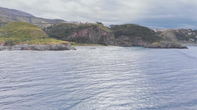 Aerial view of Arcomagno coast in Calabria Italy showing turquoise sea meeting rugged cliffs and hidden caves surrounded by lush Mediterranean vegetation symbolizing untouched natural beauty