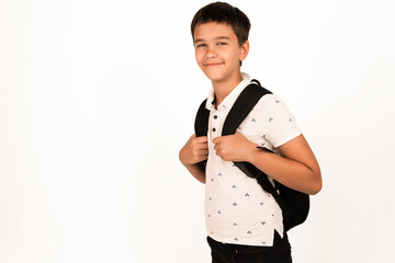 Young boy with short dark hair wearing a white patterned shirt and black backpack, isolated on white background. Suitable for education, school, student, or back to school concepts.
