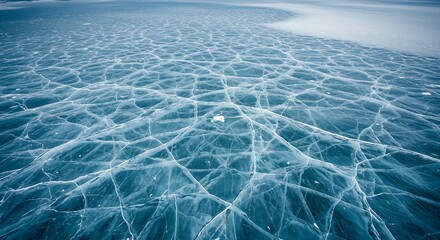 Stunning abstract patterns of a vast, frozen lake surface showcasing intricate ice cracks and crystal clear blue hues under natural light