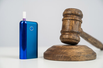Judge's gavel and electronic cigarette. Smoking ban. Tobacco heating systems. 