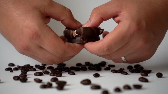 Close-up of hands breaking chocolate with stretchy filling, showcasing rich texture, melting consistency, and indulgent dessert concept with smooth pull effect.