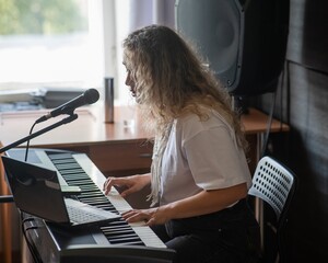 Caucasian woman singing into microphone and playing synthesizer. Online lesson on laptop. 