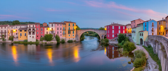 Colorful riverfront houses reflect in tranquil waters at dusk