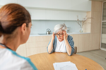 Female doctor examining older senior woman in doctor office or at home. Old woman lady patient and doctor have consultation in hospital room. Medicine healthcare medical checkup. Visit to doctor
