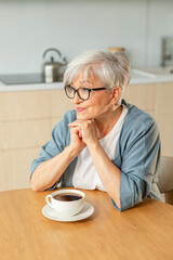Good morning. Comfort relaxed senior old elderly woman grandmother drinking hot beverage tea coffee in kitchen at home. Mature woman resting enjoy calm morning at modern home alone. Pension concept