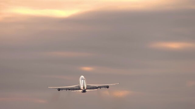 Footage of a four-engine widebody gaining altitude in a beautiful sunset or sunrise sky