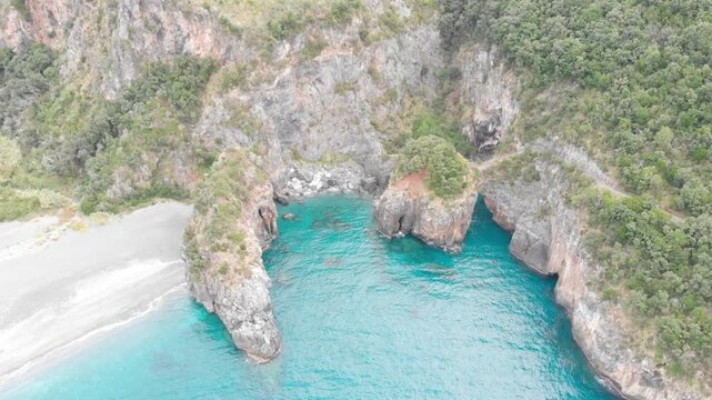 Aerial view of Arcomagno coast in Calabria Italy showing turquoise sea meeting rugged cliffs and hidden caves surrounded by lush Mediterranean vegetation symbolizing untouched natural beauty