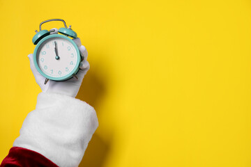 Santa Claus with alarm clock on yellow background, closeup with space for text. New Year greeting...