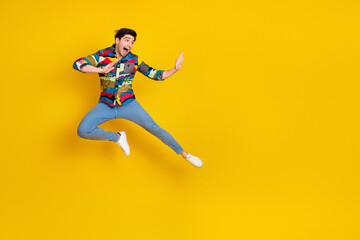 Young man jumps with colorful shirt against bright yellow background showing joy energy fashion lifestyle