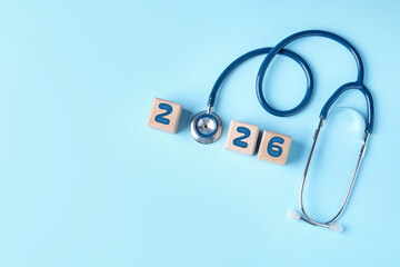 New 2026 year. Cubes with numbers and stethoscope on light blue background, top view