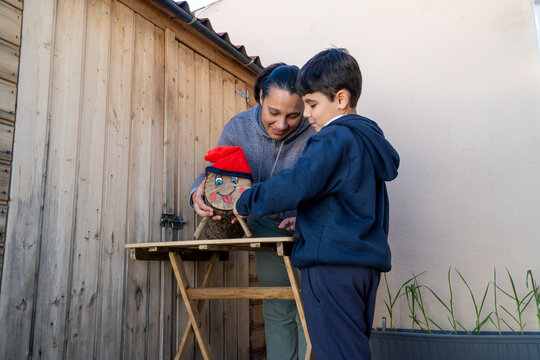 Mother and child decorating a log with a red hat during Tio de Nadal