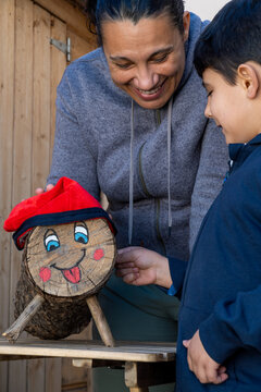 Mother and child decorating a log with a red hat during Tio de Nadal