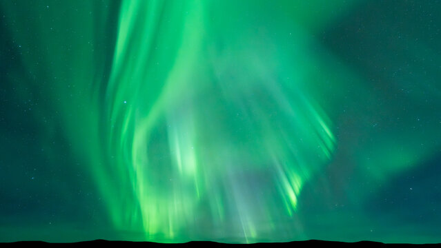 Aurora borealis dances across starry night sky