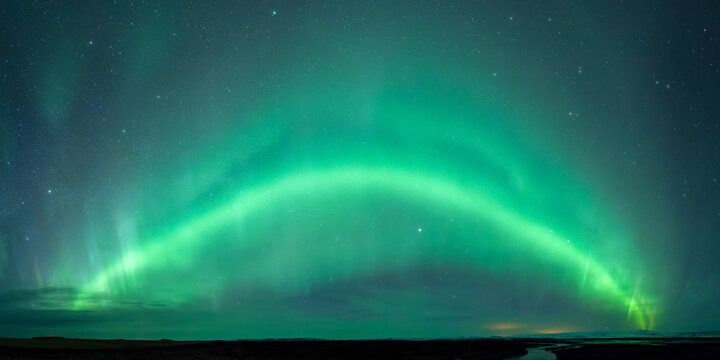 Green aurora borealis under starlit night sky