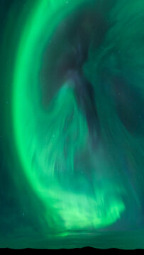 Breathtaking green aurora borealis over a dark landscape