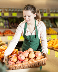 Portrait of female salesperson with tray of ripe pomegranate in a grocery store