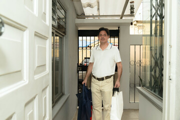 Latino adult man arriving home with gift purchases