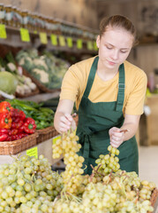 woman shopping assistant selling ripe grape in supermarket