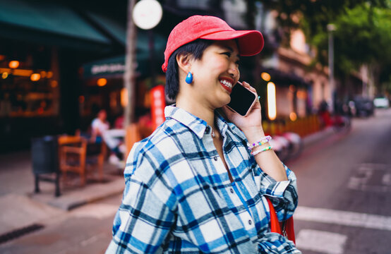 Smiling woman talks on smartphone in the street, expressing freedom and flexibility of freelance lifestyle powered by mobile technology, connectivity and joyful energy.