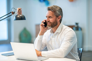 Busy businessman talking on phone in the office. Businessman using phone. Man phone conversation. Hispanic business man with smartphone at office desk. Business communication. Man reply phone call