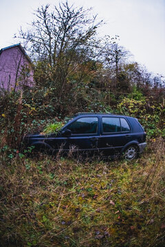 Gloomy moody scene of rusted car overtaken by nature and fallen leaves