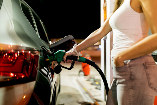 Woman refueling car at night gas station