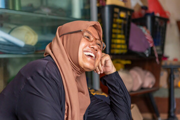 Muslim seamstress smiling at home workspace