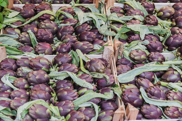 Fresh purple artichokes at a market in wooden crates