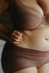 Female adult in brown lingerie with hand on waist in intimate setting
