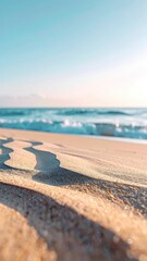 Sunlit sand ripples on a beach with soft, blurry ocean waves