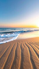 Golden sunrise over a tranquil ocean with rippled sand and gentle waves