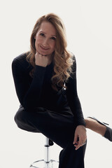 Fototapeta premium Closeup image of an elegant smiling young woman with makeup, and hairstyle in black clothes, posing in studio, isolated white background. 