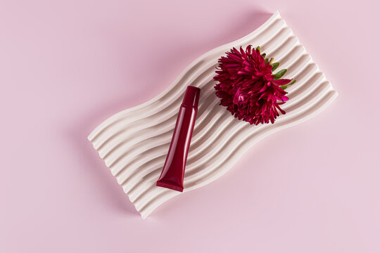 Lip balm and aster flower on a textured tray